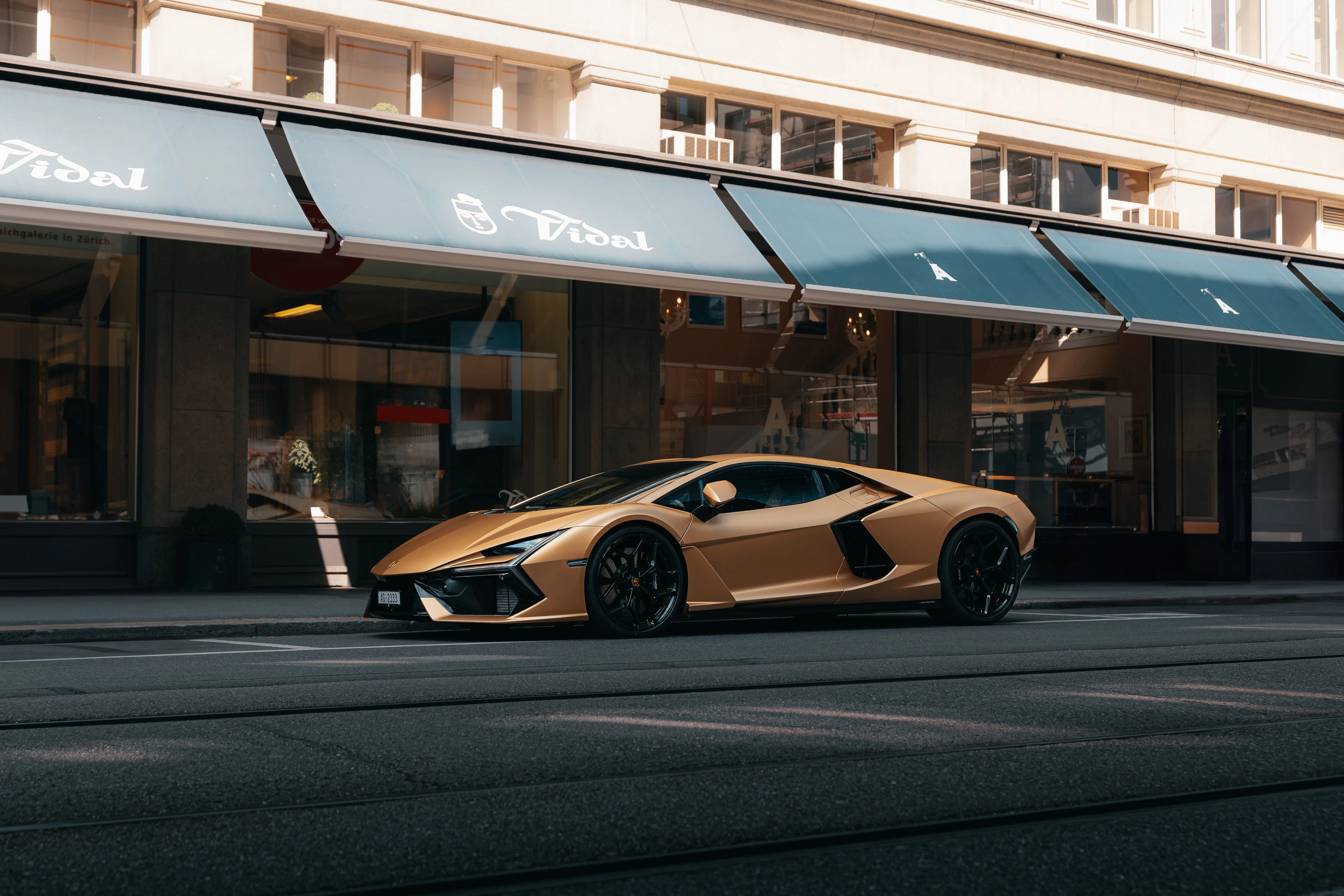 A gold Lamborghini Revuelto parked on the side of a street